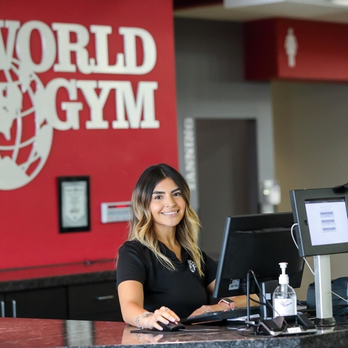 Female employee smiling at world gym check in desk