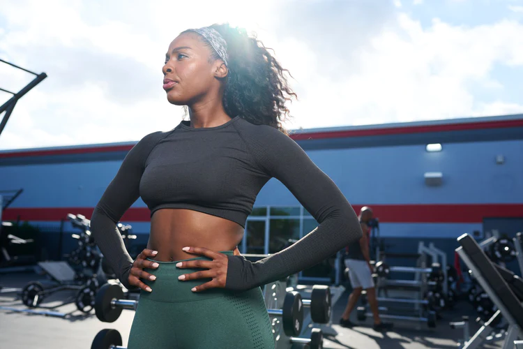 Woman standing in outdoor Gold's Gym with hands on hips