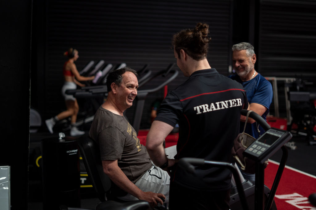 Trainer talking to smiling exerciser on exercise bike